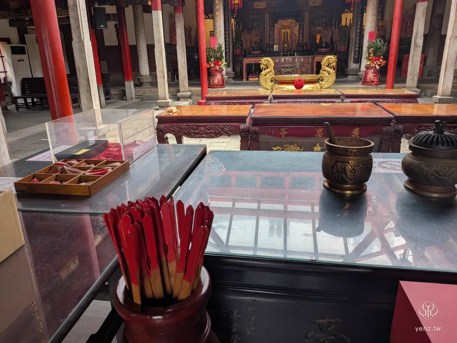義民廟籤筒桌面視角，前方有紅色籤支與香爐，背景是正殿供桌。