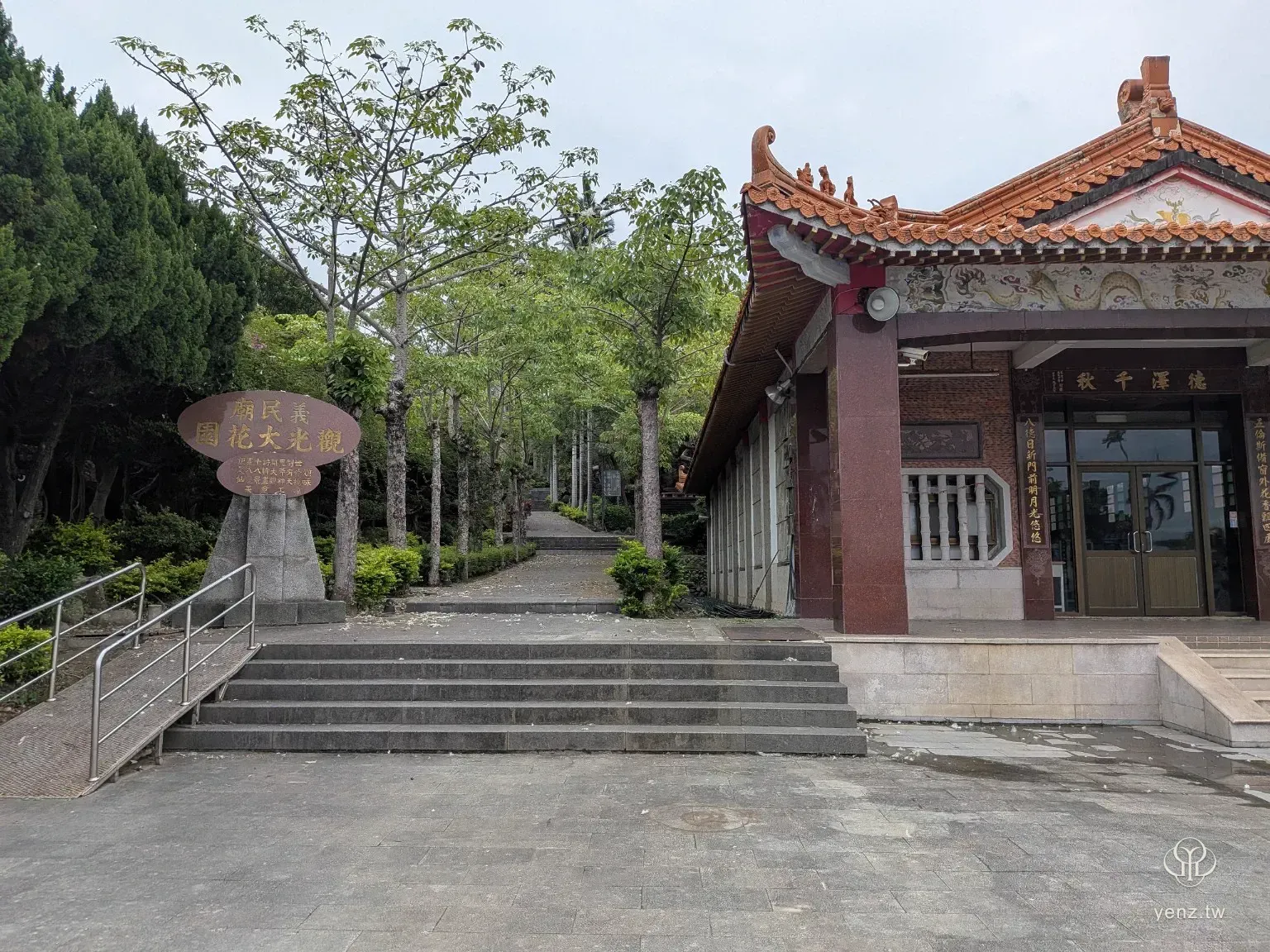 義民廟旁的觀光大花園入口，左側有標示石碑，右側是廟宇側邊建築。