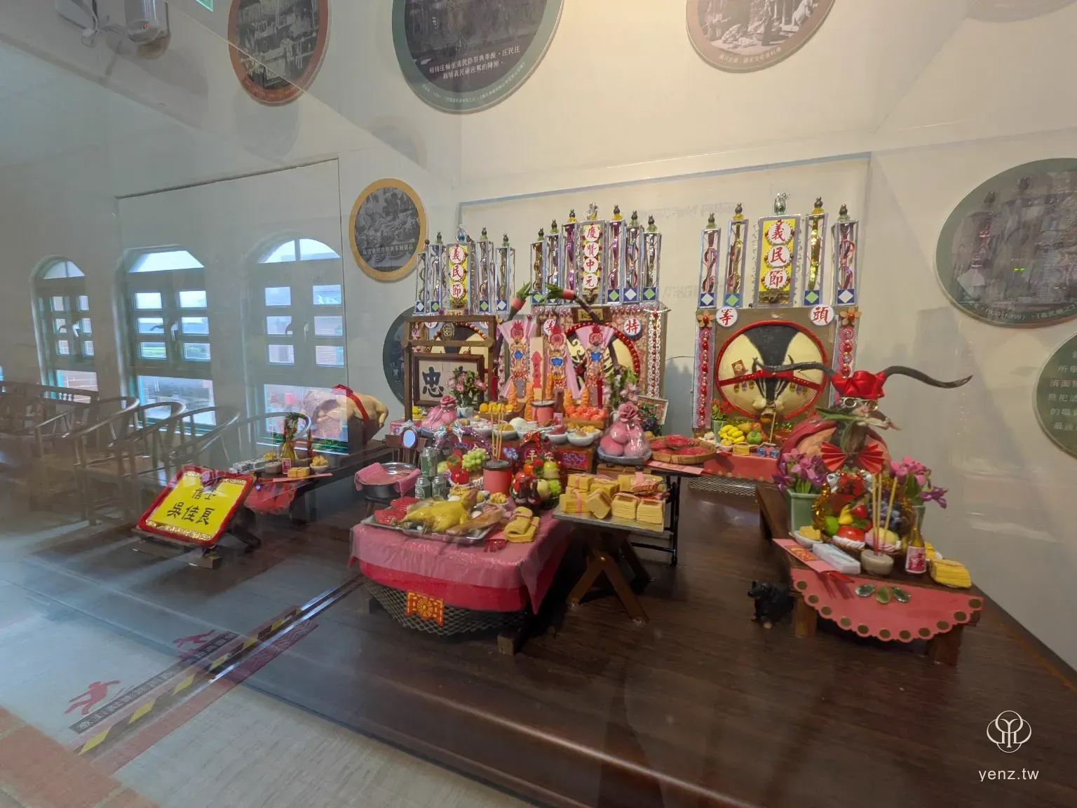 玻璃櫃中的義民祭小模型，包含供桌、供品、神豬、旗幟與祭祀場景。