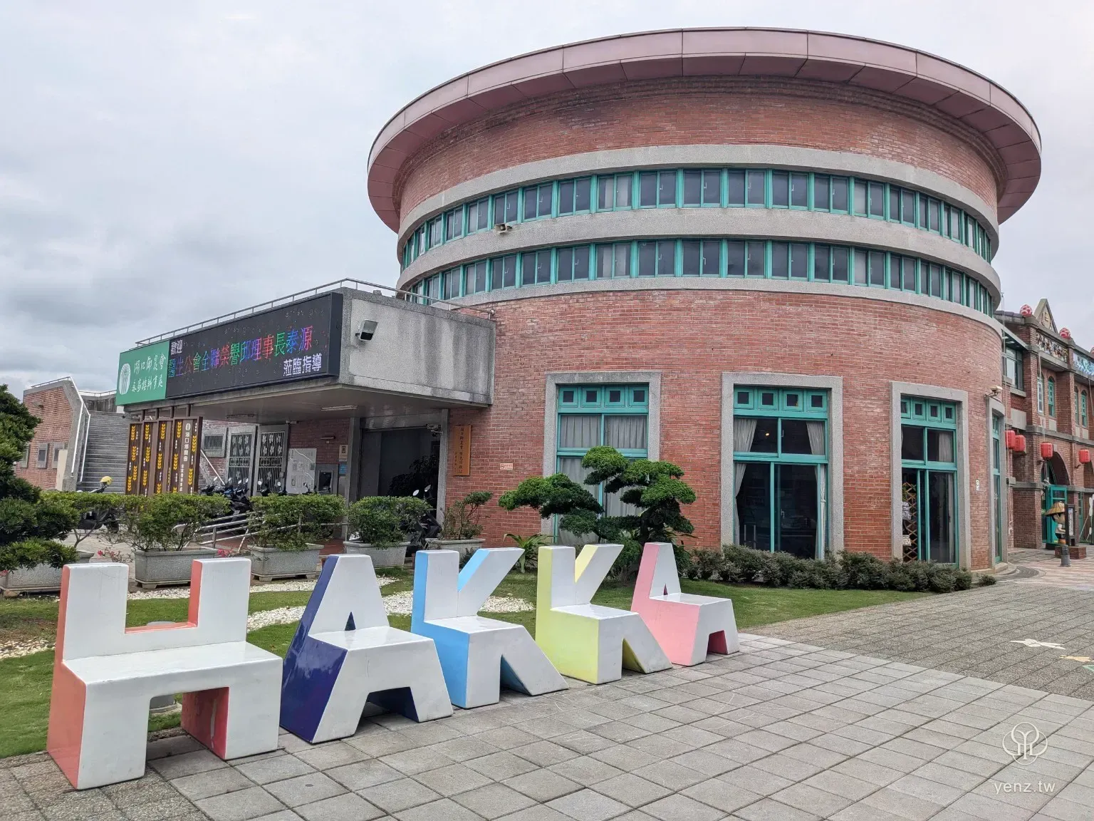 湖口好客文創園區前方的大型 HAKKA 字樣座椅，背後是圓形紅磚建築。