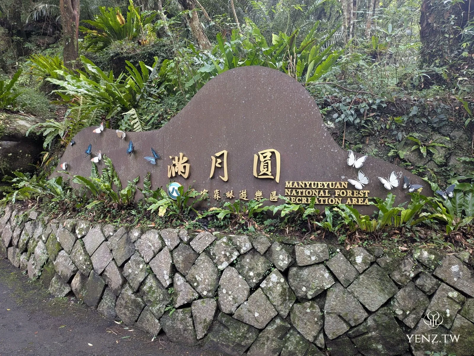 滿月圓國家森林遊樂區入口意象，巨石做成渾圓山形，旁邊飛舞著彩色金屬蝴蝶。