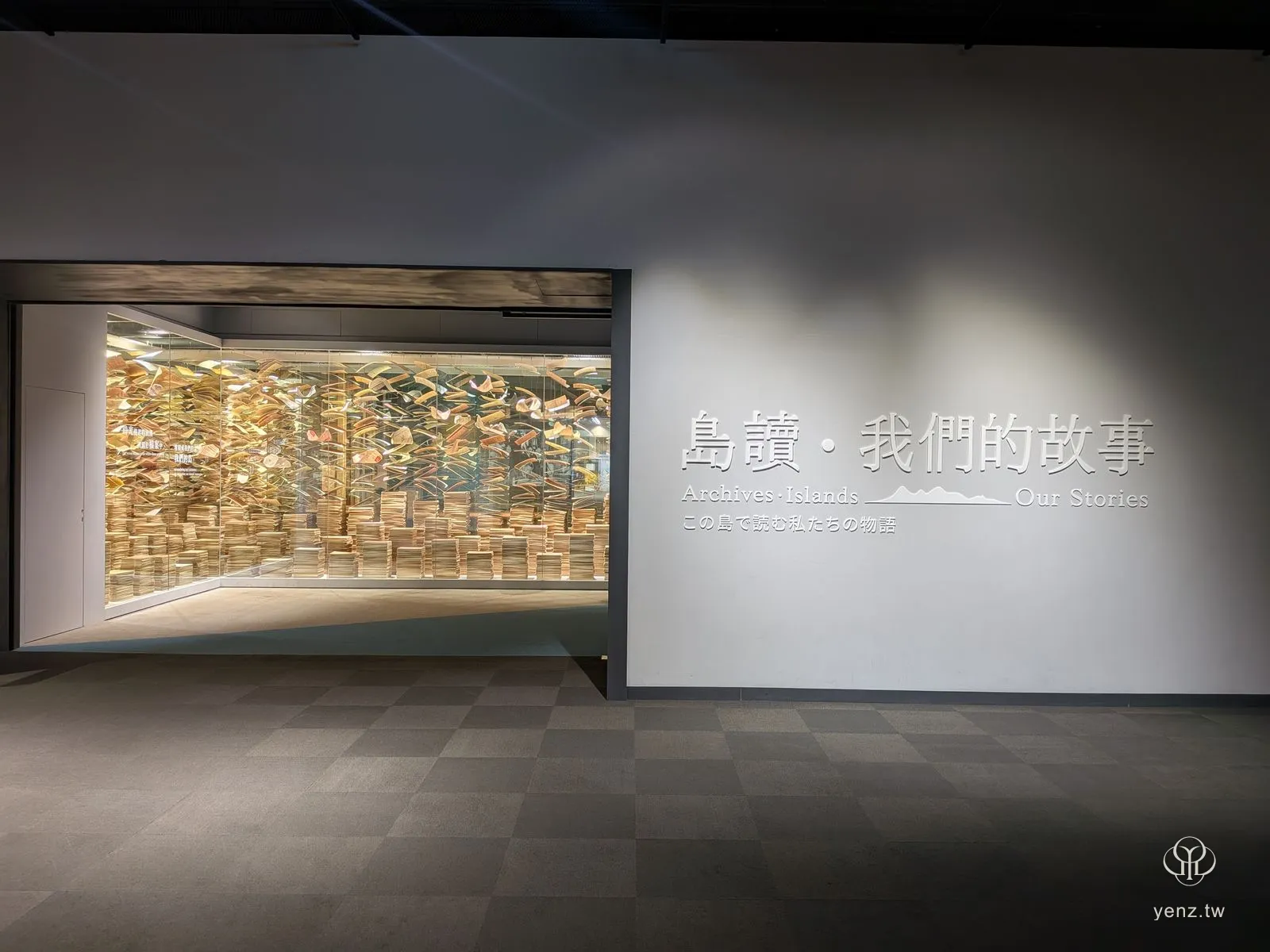 常設展正式入口「島讀‧我們的故事」與玻璃後方的檔案紙堆裝置。