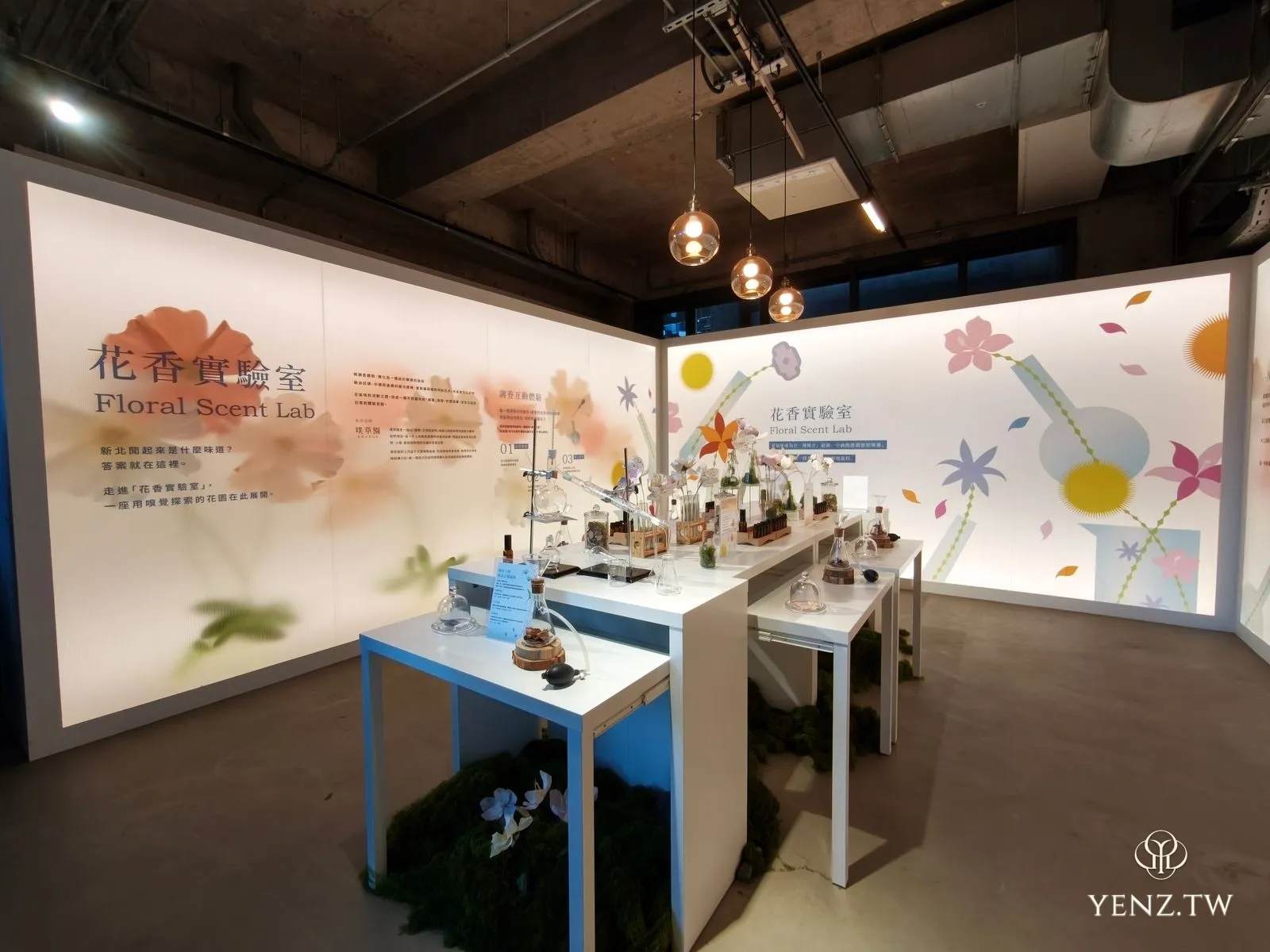 「花香實驗室」展區，白色燈箱牆面與擺著燒瓶的實驗桌，地上鋪著苔蘚。