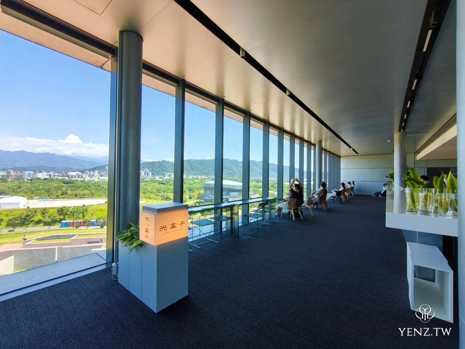 五樓「光盒子」咖啡廳，整面落地窗朝向遠山，高腳吧台與深色沙發。