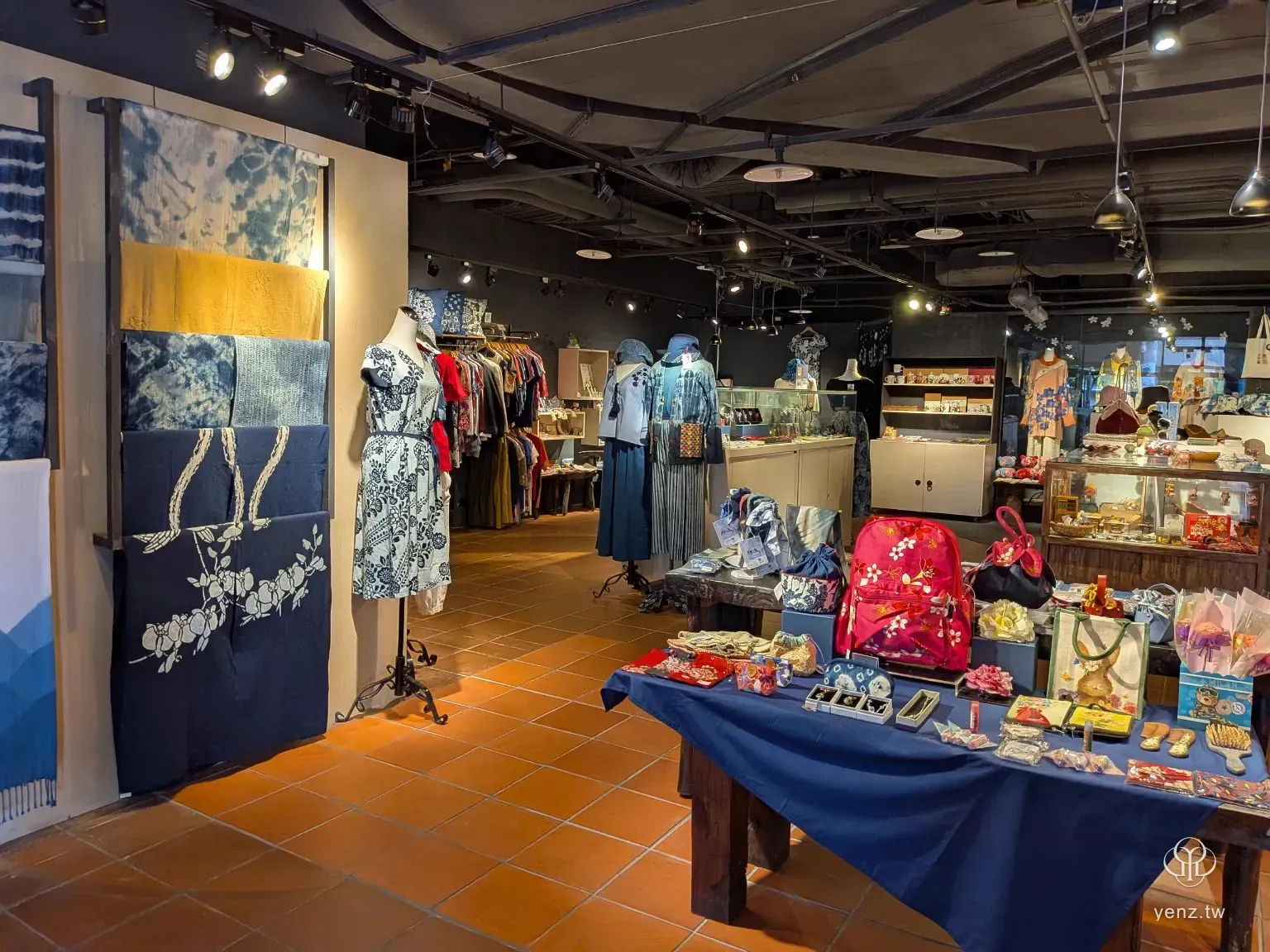 新北市客家文化園區文創商店全景，陳列藍染、花布、服飾與角色商品。