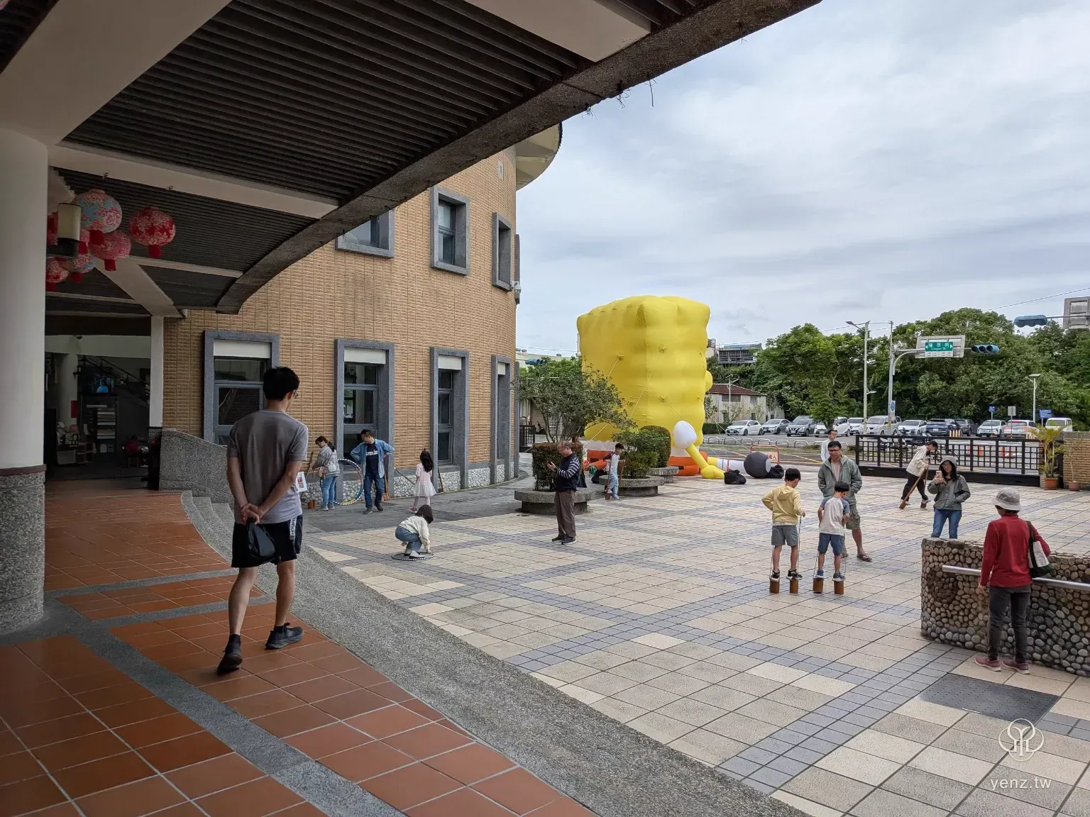 新北市客家文化園區廣場，孩子在戶外玩童玩，遠方可見活動裝置與建築。