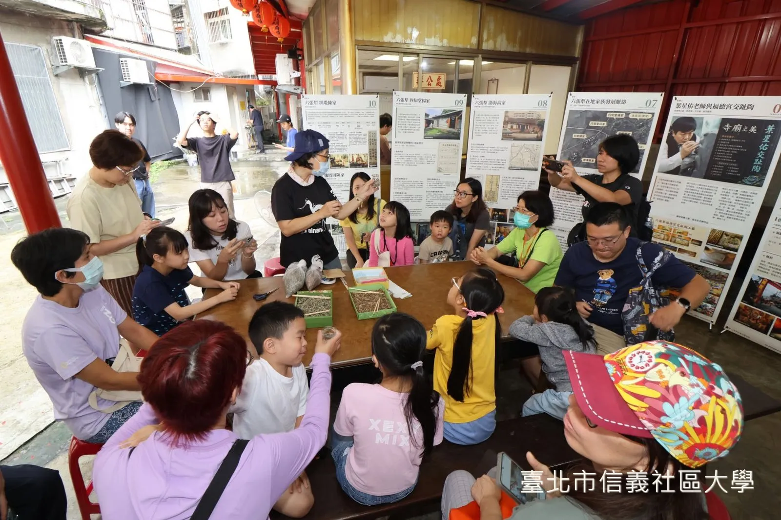 親子日「水文六張犁」摸蜆仔體驗，大人小孩圍著長桌觀察蜆。